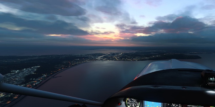A small aircraft over a coastal city at dusk in Microsoft Flight Simulator